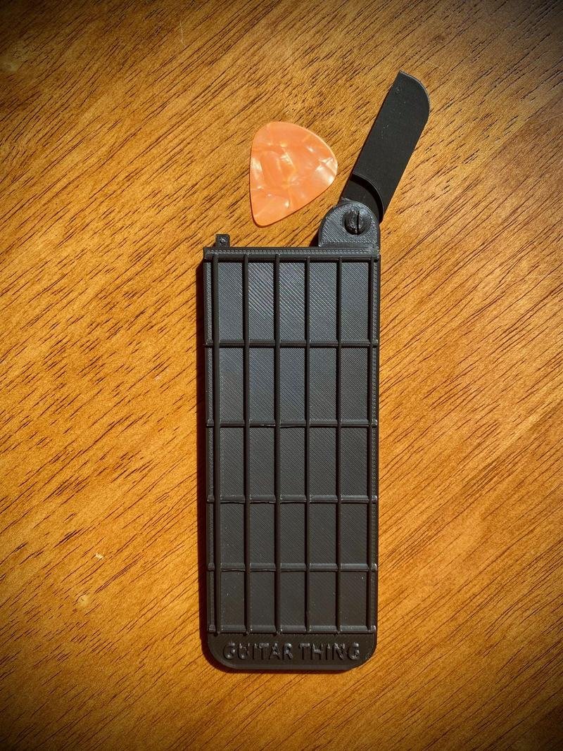Guitar Thing with its pick compartment open and a guitar pick inside